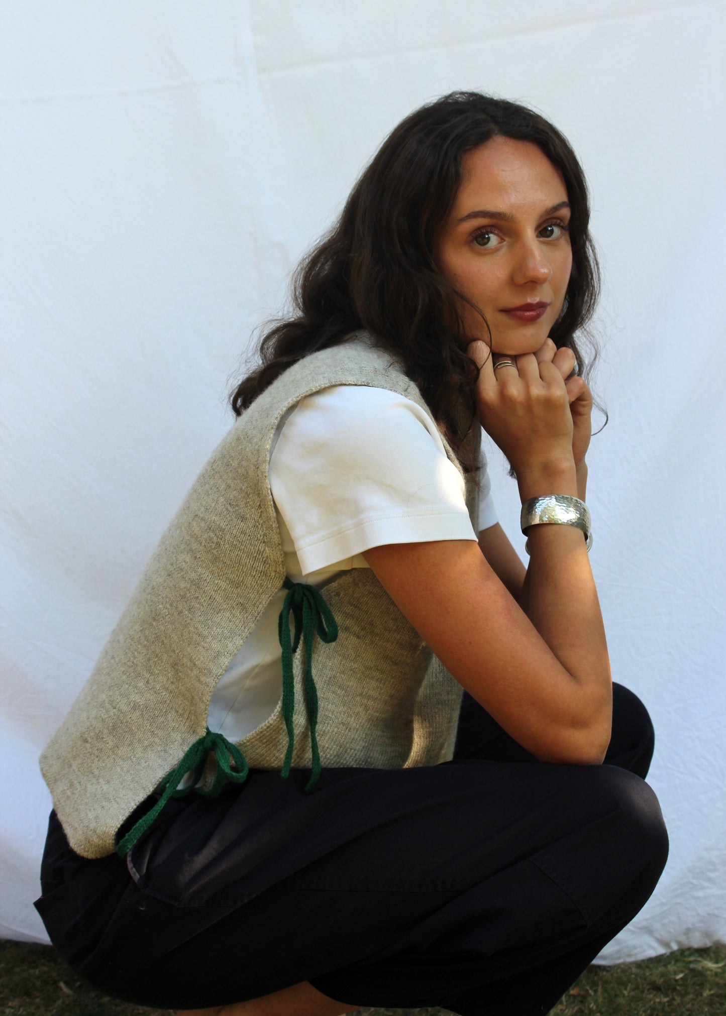 Model in undyed oat wool vest with green ties.